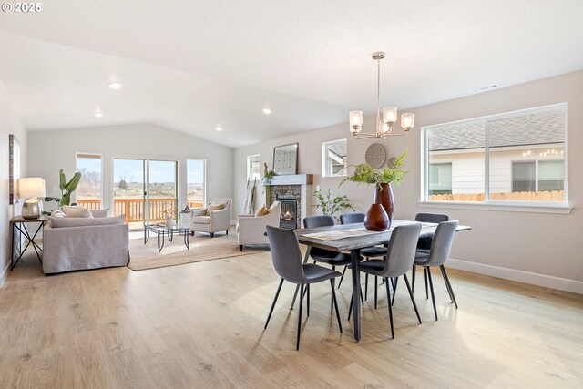 unfurnished living room featuring an inviting chandelier, a stone fireplace, light wood-type flooring, and vaulted ceiling