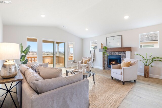 unfurnished living room with vaulted ceiling, light hardwood / wood-style flooring, and a stone fireplace