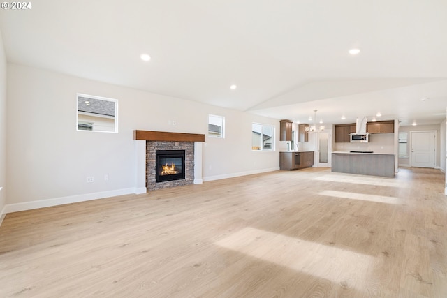 unfurnished living room featuring lofted ceiling, a fireplace, and light hardwood / wood-style flooring