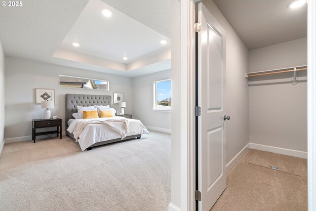 unfurnished bedroom featuring light carpet, ensuite bathroom, and a tray ceiling