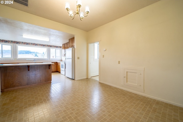 kitchen featuring a notable chandelier, kitchen peninsula, white appliances, decorative light fixtures, and a breakfast bar