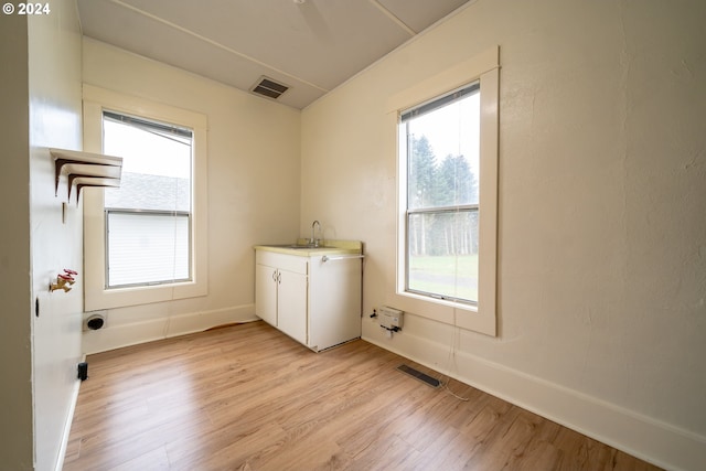 laundry room featuring cabinets, light hardwood / wood-style floors, and sink