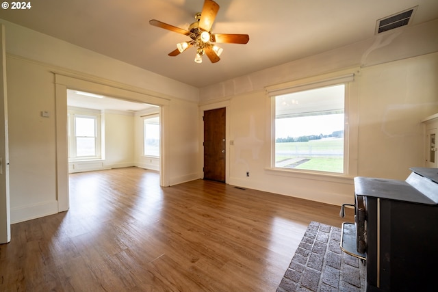 interior space with a wood stove, ceiling fan, and dark wood-type flooring