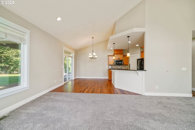 unfurnished living room featuring high vaulted ceiling, a chandelier, and dark hardwood / wood-style flooring