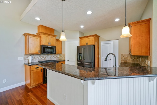 kitchen featuring high end appliances, kitchen peninsula, a kitchen bar, and decorative light fixtures