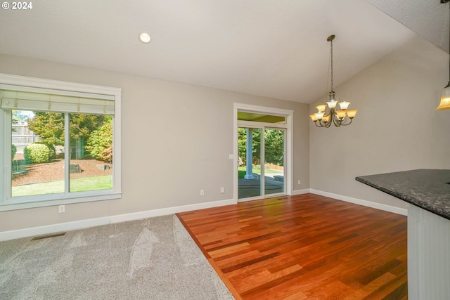 unfurnished dining area featuring lofted ceiling, dark wood-type flooring, and a chandelier