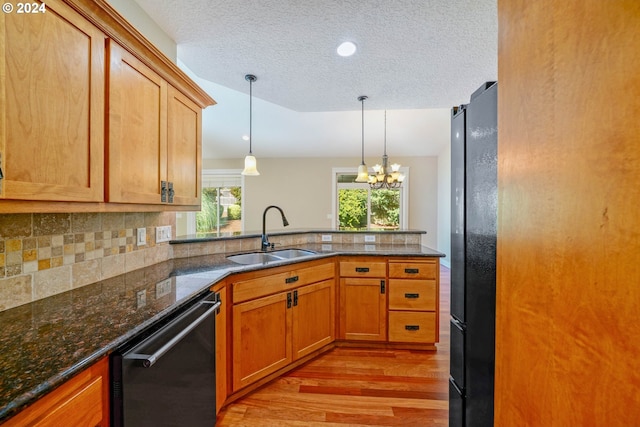 kitchen featuring light wood-type flooring, dishwasher, sink, a notable chandelier, and black refrigerator