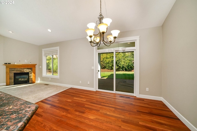 unfurnished living room featuring a notable chandelier, a fireplace, and hardwood / wood-style floors