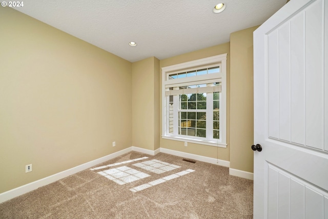 carpeted spare room featuring a textured ceiling