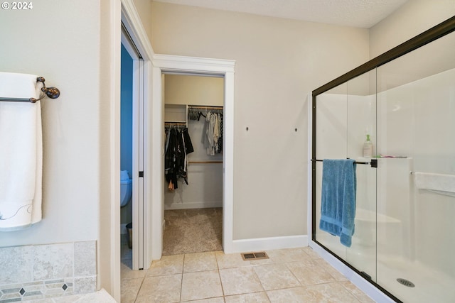 bathroom featuring a textured ceiling, an enclosed shower, and tile patterned floors