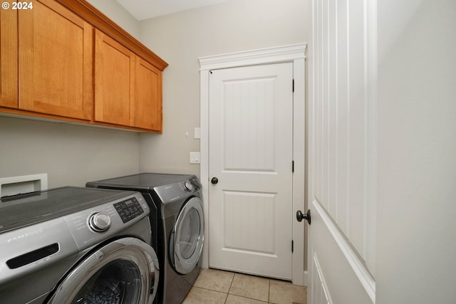 laundry area with light tile patterned floors, cabinets, and washer and dryer