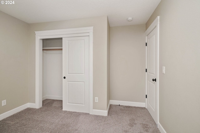 unfurnished bedroom featuring a closet, light colored carpet, and a textured ceiling