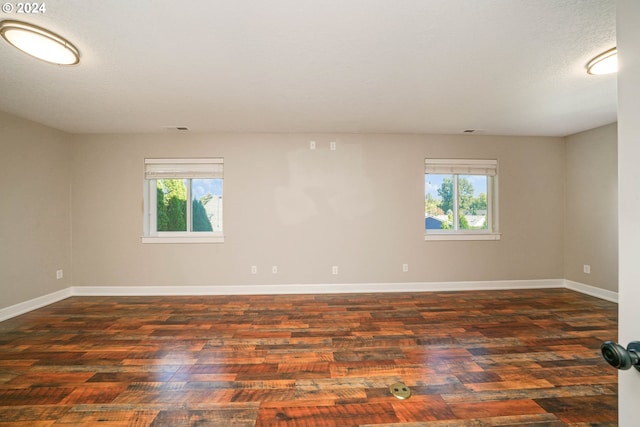 spare room featuring a textured ceiling, plenty of natural light, and dark hardwood / wood-style floors