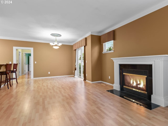 living room with a fireplace, an inviting chandelier, light hardwood / wood-style flooring, and crown molding