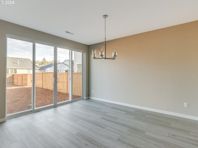 unfurnished dining area featuring light hardwood / wood-style floors and a chandelier