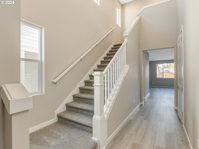 stairs with a towering ceiling and wood-type flooring