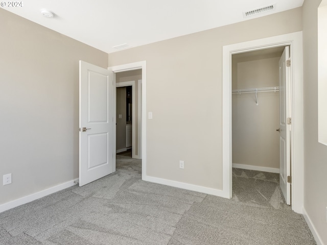 unfurnished bedroom featuring light carpet, a closet, and a walk in closet