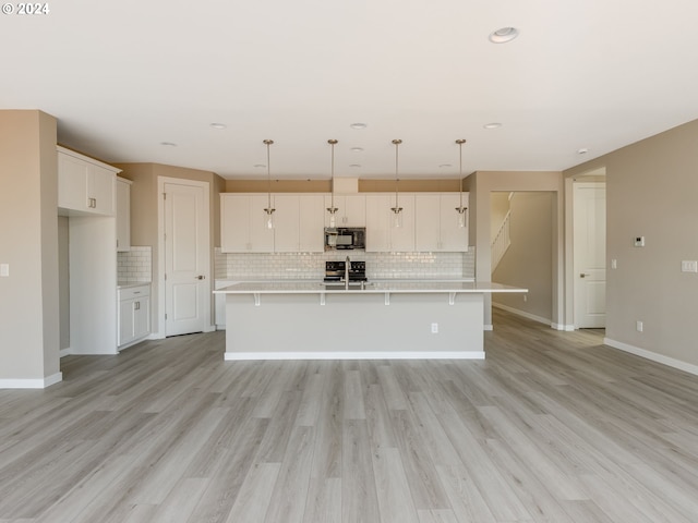 kitchen with white cabinets, a kitchen island with sink, and light hardwood / wood-style flooring