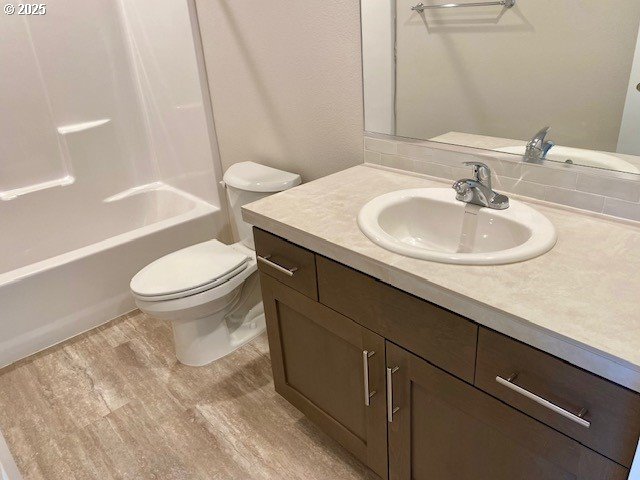 full bathroom with shower / bath combination, vanity, toilet, and wood finished floors