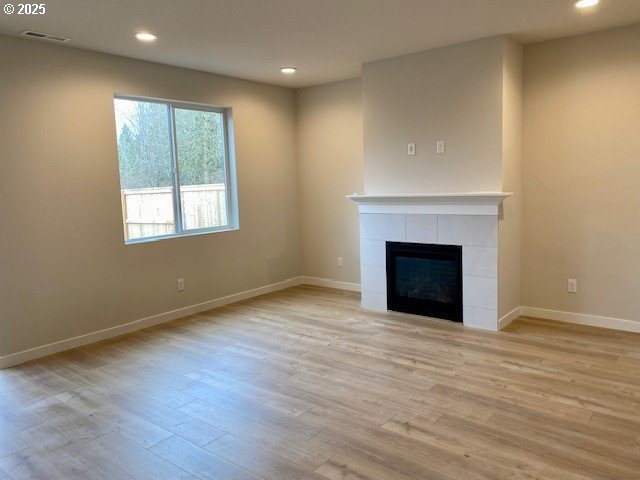 unfurnished living room with light wood-style flooring, a fireplace, and baseboards