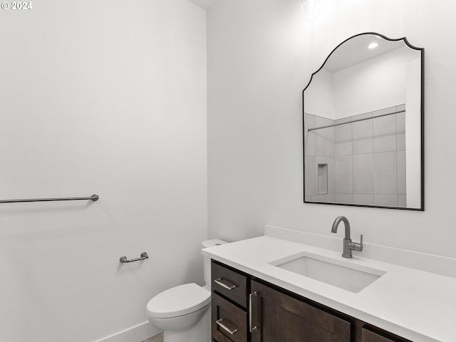 bathroom with walk in shower, vanity, and toilet