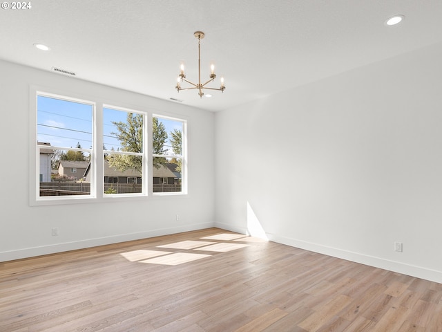 empty room featuring light wood-type flooring and a chandelier