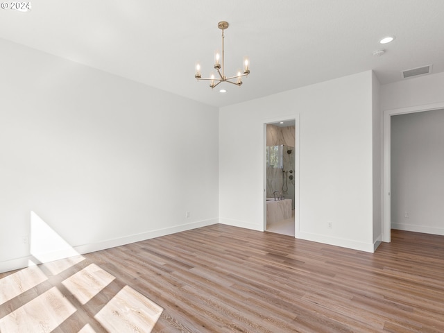 empty room with light hardwood / wood-style flooring and a chandelier