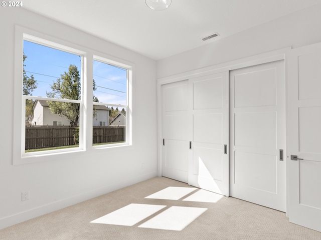 unfurnished bedroom featuring light colored carpet and a closet