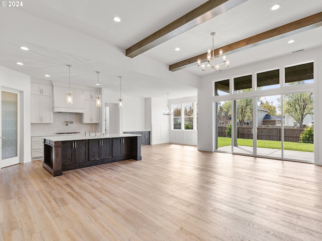 kitchen with a large island, white cabinets, light hardwood / wood-style floors, and decorative light fixtures