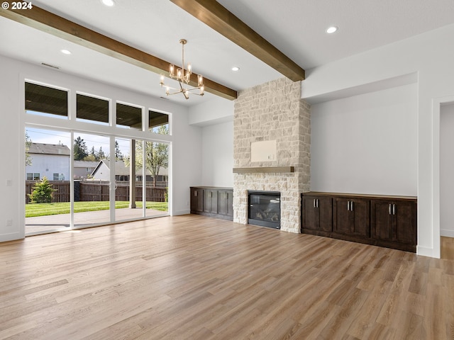 unfurnished living room with beam ceiling, light hardwood / wood-style floors, a fireplace, and an inviting chandelier