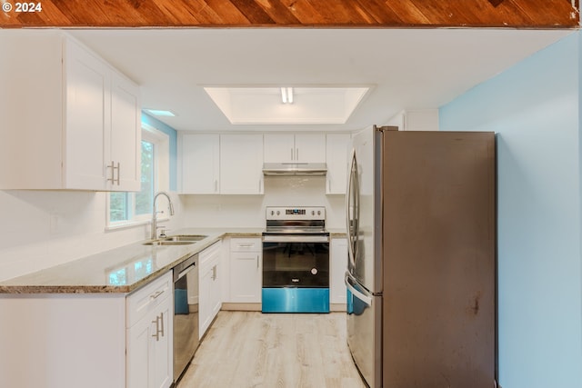 kitchen with sink, light stone countertops, light wood-type flooring, appliances with stainless steel finishes, and white cabinetry