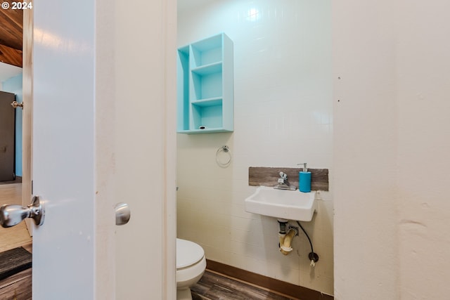 bathroom with hardwood / wood-style floors, toilet, tile walls, and sink