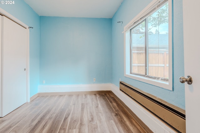 unfurnished room featuring hardwood / wood-style floors and a baseboard radiator