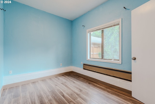 unfurnished room featuring hardwood / wood-style floors and a baseboard radiator