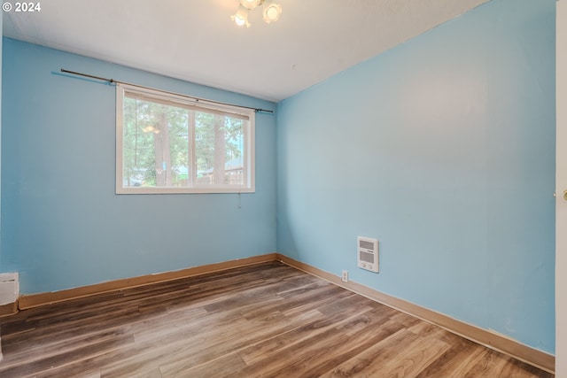 unfurnished room with wood-type flooring and heating unit