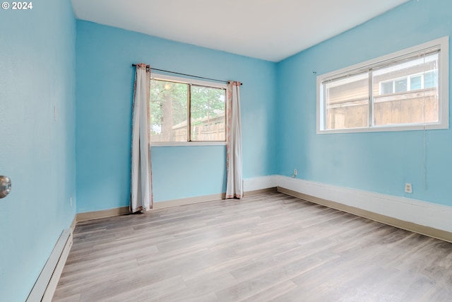 unfurnished room with light hardwood / wood-style floors and a baseboard heating unit