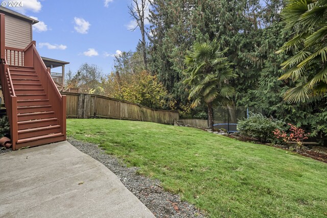 view of yard with a trampoline and a patio