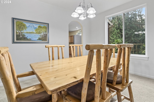 dining area with an inviting chandelier, carpet, and a healthy amount of sunlight