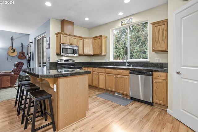 kitchen featuring a kitchen island, a kitchen bar, light hardwood / wood-style flooring, sink, and stainless steel appliances