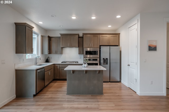 kitchen with appliances with stainless steel finishes, a center island, sink, and light wood-type flooring