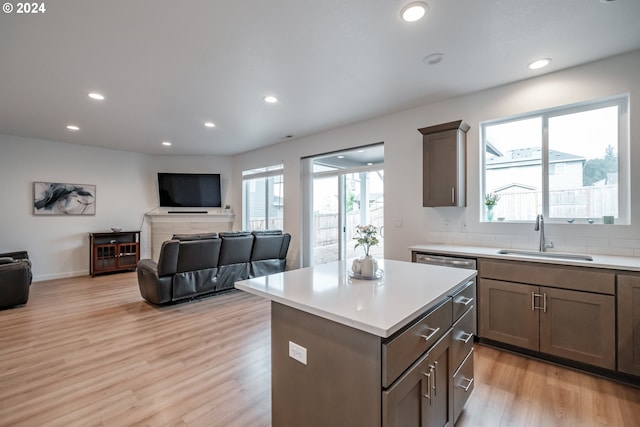 kitchen with a kitchen island, sink, and light wood-type flooring