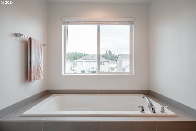 bathroom featuring tiled tub and a wealth of natural light