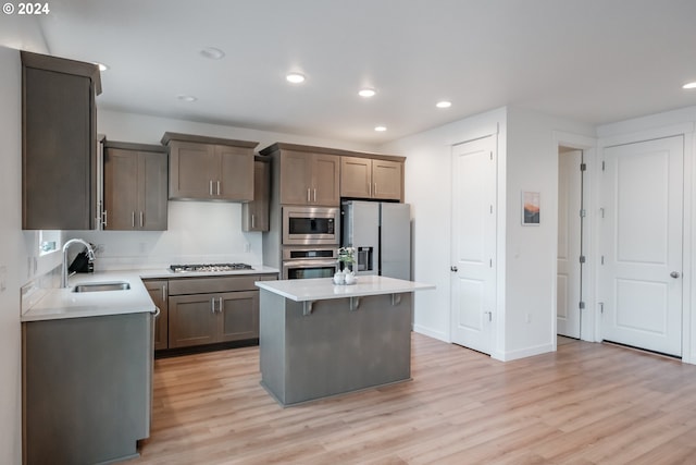 kitchen with sink, a breakfast bar area, light hardwood / wood-style flooring, a kitchen island, and stainless steel appliances