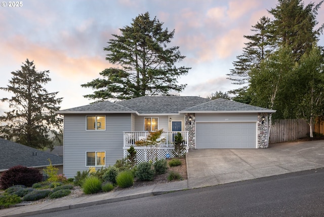 view of front of property featuring stone siding, a porch, fence, concrete driveway, and an attached garage