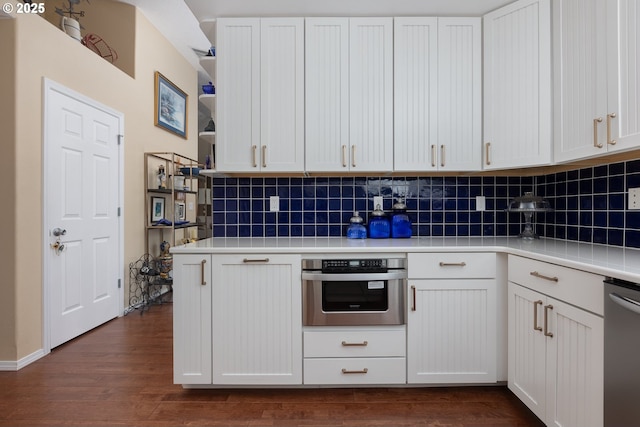 kitchen with dark wood finished floors, light countertops, appliances with stainless steel finishes, and decorative backsplash