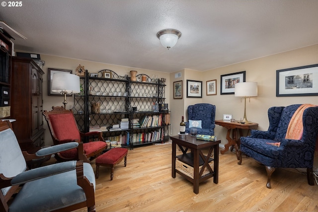 sitting room with visible vents, a textured ceiling, and light wood-style floors