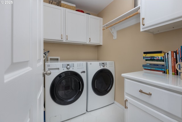 laundry area featuring separate washer and dryer, light tile patterned floors, cabinet space, and baseboards