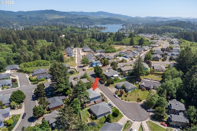 drone / aerial view with a residential view, a water and mountain view, and a wooded view