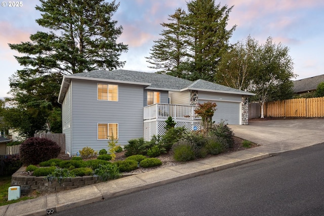 view of front of home with an attached garage, concrete driveway, and fence