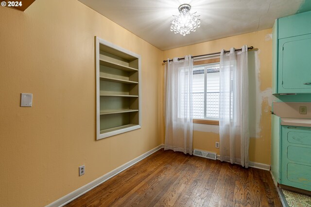 unfurnished dining area featuring stacked washer and clothes dryer, an inviting chandelier, and dark wood-type flooring